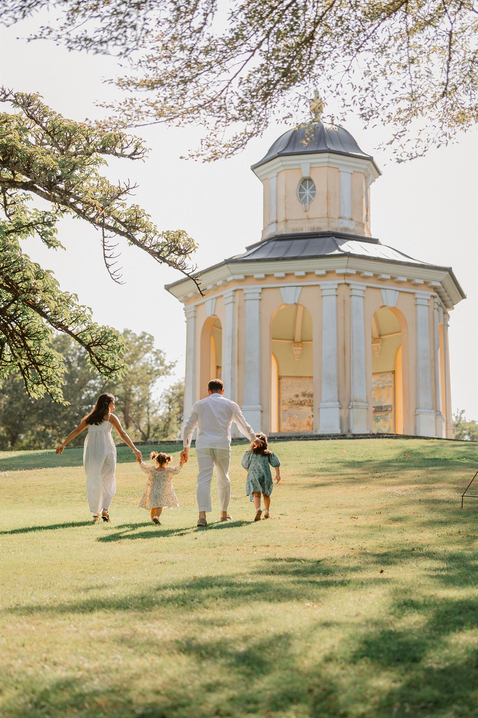 Famille main dans la main marchant vers un pavillon dans un parc, séance photo en extérieur